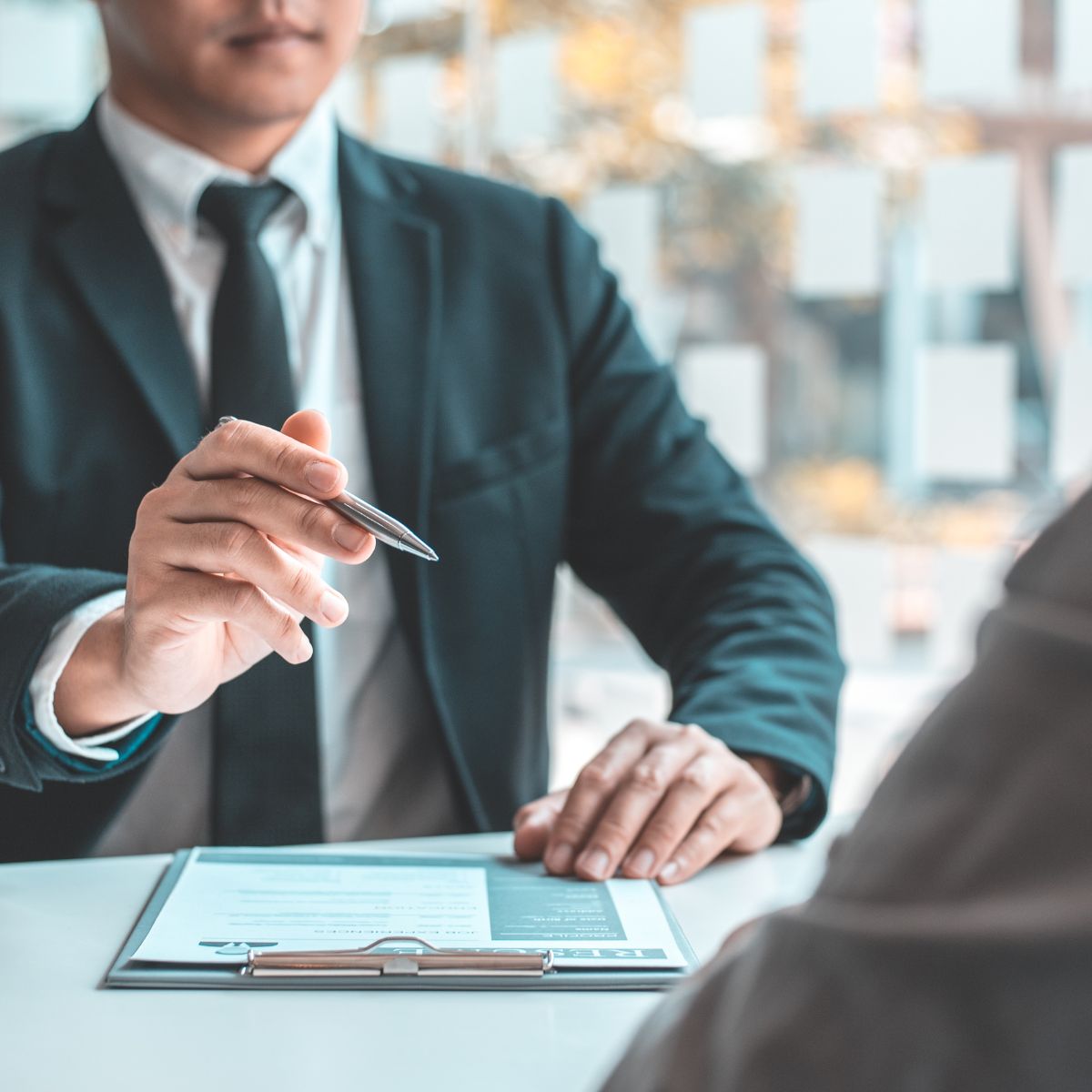 Attorney reviewing documents on a clipboard while gesturing with a pen during a client meeting about an IRS audit